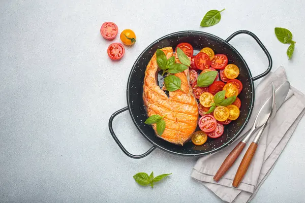 Siyah tavada ızgara somon bifteği, yanında canlı vişne domatesleri ve taze fesleğen yaprakları, sağlıklı beslenme ya da diyet konsepti, kopyalama alanı.
