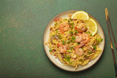 Karides, fıstık, yeşil soğan, limon dilimleri ile süslenmiş Tayland erişteleri ve kırsal yeşil arka planda servis edilen çubuklarla Tayland mutfağı, fotokopi alanı.
