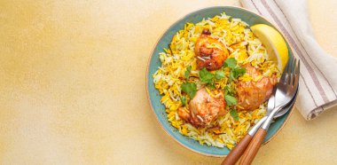 Lezzetli Hint usulü biryani tavuğu, taze kişniş ve limonla süslenmiş, bej bir masada fotokopi alanı olan bir kasede. Hindistan 'ın otantik yemeği