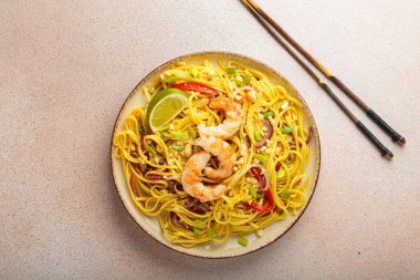 Karidesli, fıstıklı, limonlu ve doğranmış sebzeli Tayland yemeği açık bej arka plan manzaralı çubuklar, Tayland yemeği.