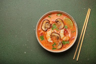 Karidesli, mantarlı, limonlu ve yeşil arka planda yemek çubuklarıyla servis edilen kişniş çorbası Tayland 'ın lezzetli ve aromatik geleneksel bir yemeğidir.