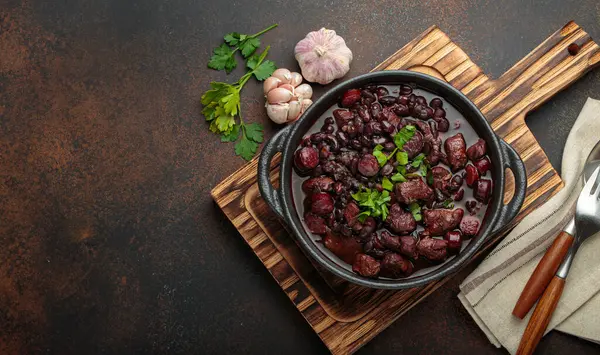 Brezilya feijoada 'sı, sağlıklı bir siyah fasulye güveci, çeşitli et kesimleri, ve sosis, taze maydanozla süslenmiş, kırsal döküm demir bir tencerede, servis edilmeye hazır.