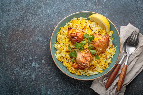 Lezzetli Hint usulü biryani tavuğu, taze kişniş ve limonla süslenmiş, fotokopi alanı olan bir kırsal masada. Hindistan 'ın otantik yemeği
