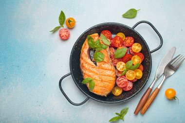 Siyah tavada ızgara somon bifteği, yanında canlı vişne domatesleri ve taze fesleğen yaprakları, sağlıklı beslenme ya da diyet konsepti, kopyalama alanı.