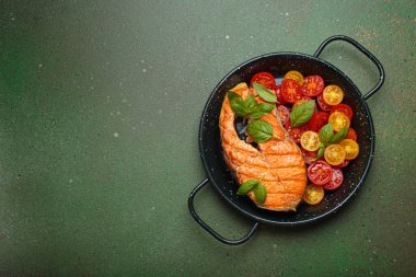 Siyah tavada ızgara somon bifteği, yanında canlı vişne domatesleri ve taze fesleğen yaprakları, sağlıklı beslenme ya da diyet konsepti, kopyalama alanı.