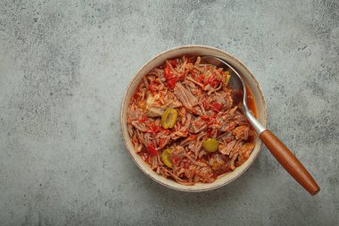 Geleneksel Küba yemeği olan Ropa vieja, yukarıdan gri kırsal arkaplan üzerinde beyaz pirinç, domates sosu ve yeşil zeytinlerle servis edilir.