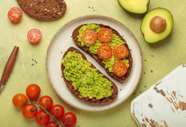 Sağlıklı bir kahvaltı veya atıştırmalık olarak tabakta tam tahıllı çavdar ekmeği, yeşil bezelye püresi ve siyah susam tohumlu kiraz domatesleri servis edilir.