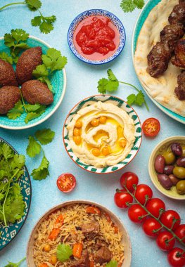 Lübnan yemekleri ve mezzayla dolu canlı bir masa, içinde et kebabı, falafel, kibbe, humus, sambousek, pilav, zeytin bulunan. Orta Doğu ya da Arap yemekleri