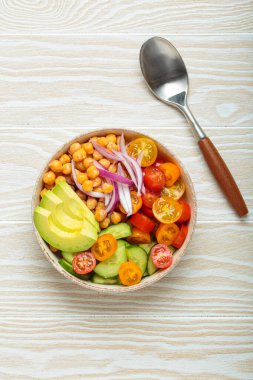 Sağlıklı nohut salatası, olgun avokado, sulu vişneli domates, salatalık ve kırmızı soğan dilimleri. Besleyici ve sağlıklı bir yemek için mükemmel.