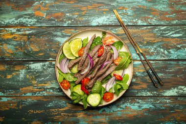 Geleneksel Tayland sığır eti salatası, sebzeli ve naneli. Kırsal ahşap arka planda servis edilmiş, sağlıklı egzotik Asya yemeği..