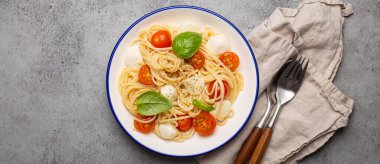 Lezzetli ve taze spagetti kiraz domatesli ve mozzarella peynirli, biber ve fesleğenle tatlandırılmış, bir tabak içinde servis edilen,