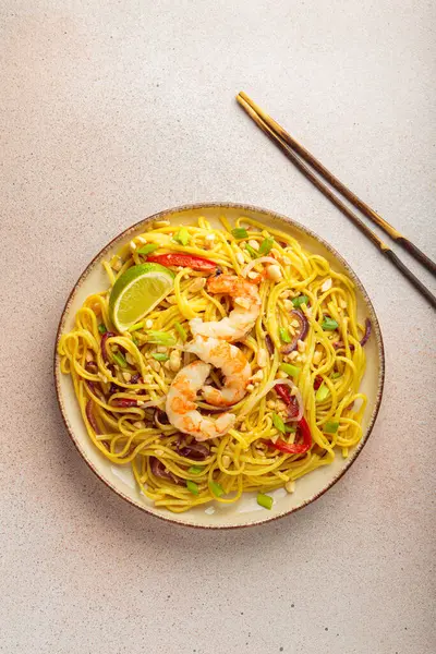 Karidesli, fıstıklı, limonlu ve doğranmış sebzeli Tayland yemeği açık bej arka plan manzaralı çubuklar, Tayland yemeği.