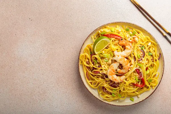 Karides, fıstık, limon ve doğranmış sebzeli Tayland yemeği açık bej arka plan manzaralı çubuklar, Tayland yemeği. Boşluğu kopyala