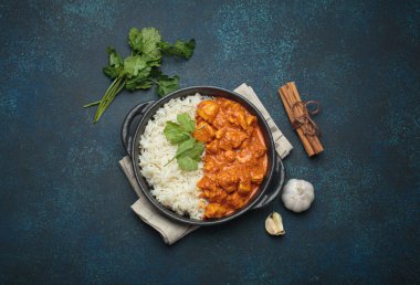Hintli tavuk tikka masala kremalı domates soslu, basmati pilavı, taze kişniş ve baharatla servis ediliyor, geleneksel Hint yemeği.