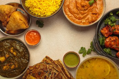 Köri, tandır tavuğu, tavuk tikka masala, dal, Palak paneer, paratha, pilav, samosa dahil olmak üzere bej masadaki çeşitli Hint yemeklerinin genel görünümü. Hindistan mutfağı, kopyalama alanı