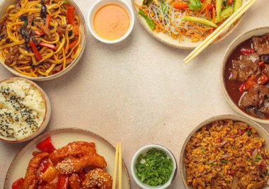 Çeşitli Çin yemekleri, tatlı ve ekşi tavuk, soslu sığır eti, erişte, kızarmış pirinç, salata ve ahşap çubuklar merkezi boş bir alanda çerçeve oluşturuyorlar. Boşluğu kopyala