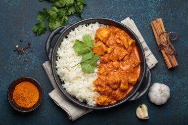 Hintli tavuk tikka masala kremalı domates soslu, basmati pilavı, taze kişniş ve baharatla servis ediliyor, geleneksel Hint yemeği.
