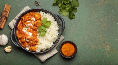 Aromatik Hint tavuğu tikka masala pilav ve kişniş, zerdeçal, sarımsak, tarçın çubukları, geleneksel Hint yemeği üst görünümü, kopyalama alanı ile servis edilir.