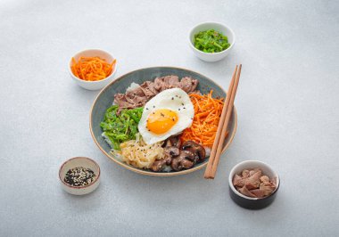 Bibimbap, haşlanmış pirinçli otantik Kore yemeği, kızarmış yumurta, sığır eti, renkli sebzeler, yemek çubuklarıyla geleneksel Kore yemeği.