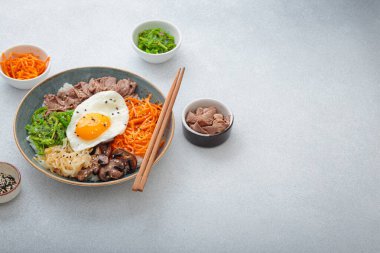 Bibimbap, haşlanmış pirinçli otantik Kore yemeği kızarmış yumurta, sığır eti, renkli sebzeler, hafif arka planda Kore yemeği, kopyalama alanı.