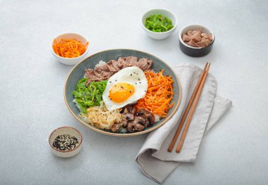 Bibimbap, haşlanmış pirinçli otantik Kore yemeği, kızarmış yumurta, sığır eti, renkli sebzeler, yemek çubuklarıyla geleneksel Kore yemeği.