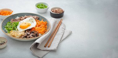 Bibimbap, haşlanmış pirinçli otantik Kore yemeği kızarmış yumurta, sığır eti, renkli sebzeler, hafif arka planda Kore yemeği, kopyalama alanı.