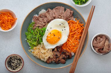 Bibimbap, haşlanmış pirinçli otantik Kore yemeği omlet, sığır eti, renkli sebzeler, açık arkaplanda geleneksel Kore yemeği.