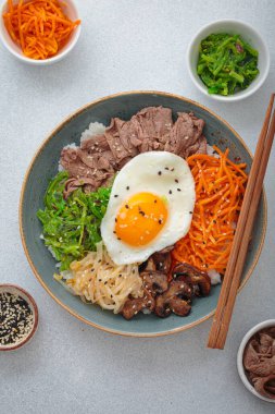Bibimbap, haşlanmış pirinçli otantik Kore yemeği omlet, sığır eti, renkli sebzeler, açık arkaplanda geleneksel Kore yemeği.