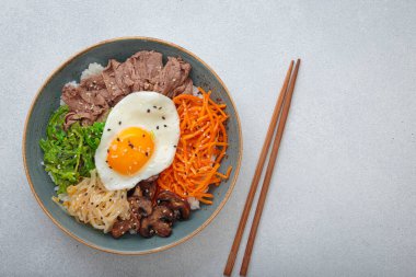 Bibimbap, haşlanmış pirinçli otantik Kore yemeği omlet, sığır eti, renkli sebzeler, açık arkaplanda geleneksel Kore yemeği, kopyalama alanı.