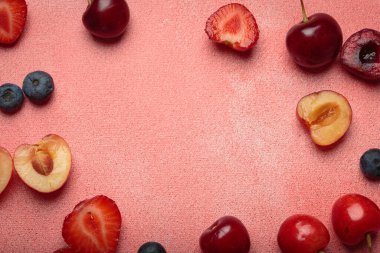 Çilekler, kirazlar, böğürtlenler ve muzlar da dahil olmak üzere canlı taze meyve aranjmanı kopyalanmış pembe bir yüzey üzerinde