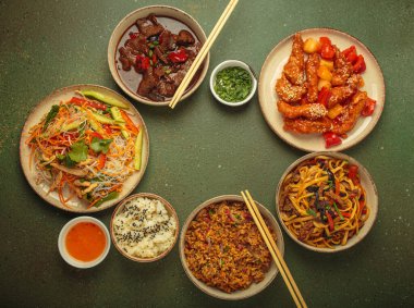 Çeşitli Çin yemekleri, tatlı ve ekşi tavuk, soslu sığır eti, erişte, kızarmış pirinç, salata ve ahşap çubuklar merkezi boş bir alanda çerçeve oluşturuyorlar. Boşluğu kopyala