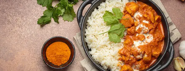 Aromatik Hint tavuğu tikka masala pilav ve kişniş, zerdeçal, sarımsak, tarçın çubukları, geleneksel Hint yemeği üst görünümü, kopyalama alanı ile servis edilir.