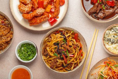 Çeşitli Çin yemekleri, tatlı ve ekşi tavuk, soslu sığır eti, erişte, kızarmış pirinç, salata ve ahşap çubuklar. Çin ya da Asya restoranı konsepti