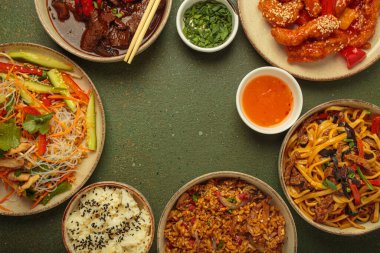 Çeşitli Çin yemekleri, tatlı ve ekşi tavuk, soslu sığır eti, erişte, kızarmış pirinç, salata ve ahşap çubuklar merkezi boş bir alanda çerçeve oluşturuyorlar. Boşluğu kopyala