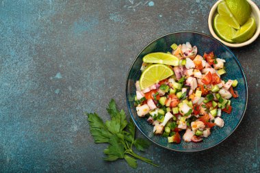 Taze ve canlı Peru deniz ürünleri ceviche ile karides, ahtapot, domates, salatalık ve maydanoz, yukarıdan gelen taş bir arka planda limonla servis edilen Peru yemeği. Boşluğu kopyala