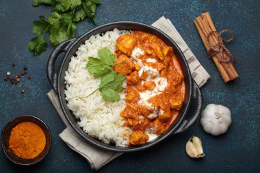 Hintli tavuk tikka masala kremalı domates soslu, basmati pilavı, taze kişniş ve baharatla servis ediliyor, geleneksel Hint yemeği.