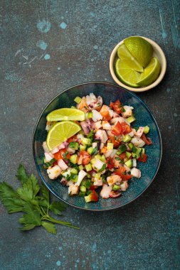 Taze ve canlı Peru deniz ürünleri ceviche ile karides, ahtapot, domates, salatalık ve maydanoz, yukarıdaki taştan bir arka planda limonla servis edilmiş, Peru yemeği.