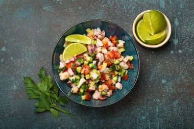 Taze ve canlı Peru deniz ürünleri ceviche ile karides, ahtapot, domates, salatalık ve maydanoz, yukarıdaki taştan bir arka planda limonla servis edilmiş, Peru yemeği.