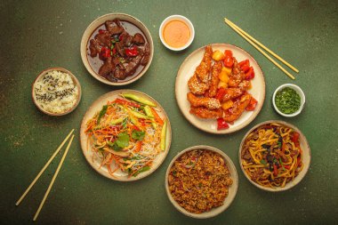 Çeşitli Çin yemekleri, tatlı ve ekşi tavuk, soslu sığır eti, erişte, kızarmış pirinç, salata ve ahşap çubuklar. Çin ya da Asya restoranı konsepti