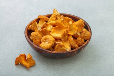 Kırsal ahşap bir kasede taze chanterelle mantarları, gri bir arka planda, sıcak ve davetkar bir sonbahar sahnesi mutfak için mükemmel.