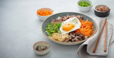 Bibimbap, haşlanmış pirinçli otantik Kore yemeği kızarmış yumurta, sığır eti, renkli sebzeler, hafif arka planda Kore yemeği, kopyalama alanı.