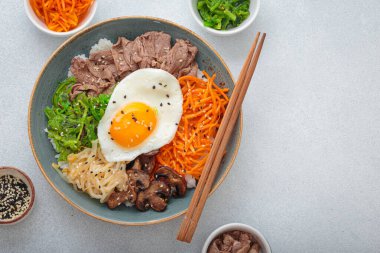 Bibimbap, haşlanmış pirinçli otantik Kore yemeği omlet, sığır eti, renkli sebzeler, açık arkaplanda geleneksel Kore yemeği, kopyalama alanı.