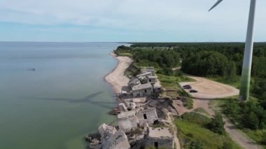 Liepaja Kuzey Kaleleri üzerinde uçan hava görüntüleri, Letonya 'daki Baltık deniz kıyısındaki eski terk edilmiş kaleler. Büyük rüzgar türbini dönüyor