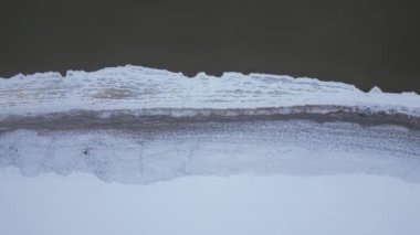 Aerial top down shot flying above along sea shoreline in winter