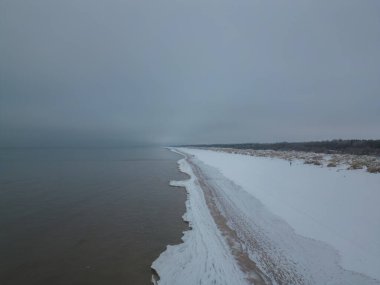 Aerial view of snow covered beach and dunes and dark and calm sea