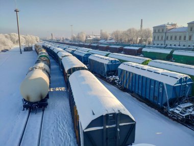 Karla kaplı yük vagonları ile dolu tren istasyonu. Kışın tren istasyonu..