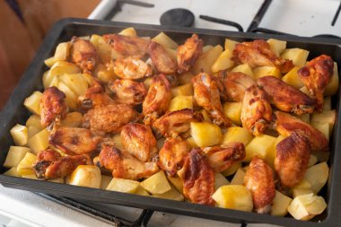 Taze kavrulmuş haşlanmış patates ve metal tavada tavuk kanadı.