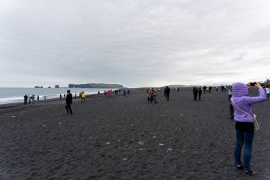 Reynisfjara Kara Kum Sahili, İzlanda - 06.22.2023: İzlanda 'da Reynisfjara Kara Kum Sahili' nde yürüyen insanlar