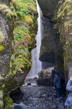 İzlanda 'daki kayalıkların arkasında Gljufrafoss veya Gljufrabui şelalesinin fotoğraflarını çeken turistler