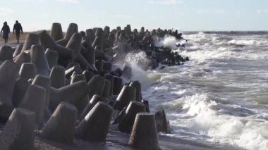 Dalgalar, gri beton tetrapodlardan oluşan dalgalara çarpıyor. Liepaja, Letonya. Liepjas Ziemelu mol